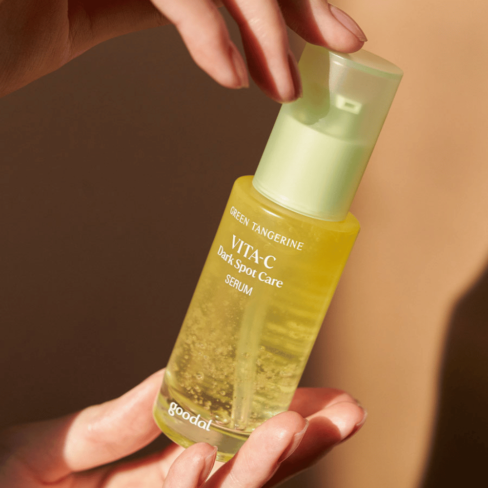 Osoba trzymająca butelkę Green Tangerine Vita C Dark Spot Care Serum 40ml od Goodal na hiperpigmentację i pielęgnację ciemnych plam.