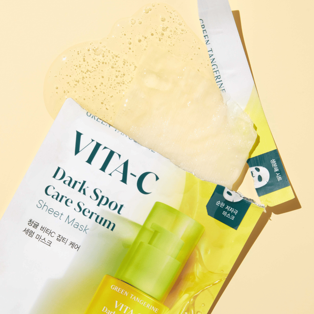 Otwarta paczka VITA-C Dark Spot Care Serum Maseczka w płachcie z maską na twarz na górze i zieloną butelką serum, wszystko na żółtym tle.