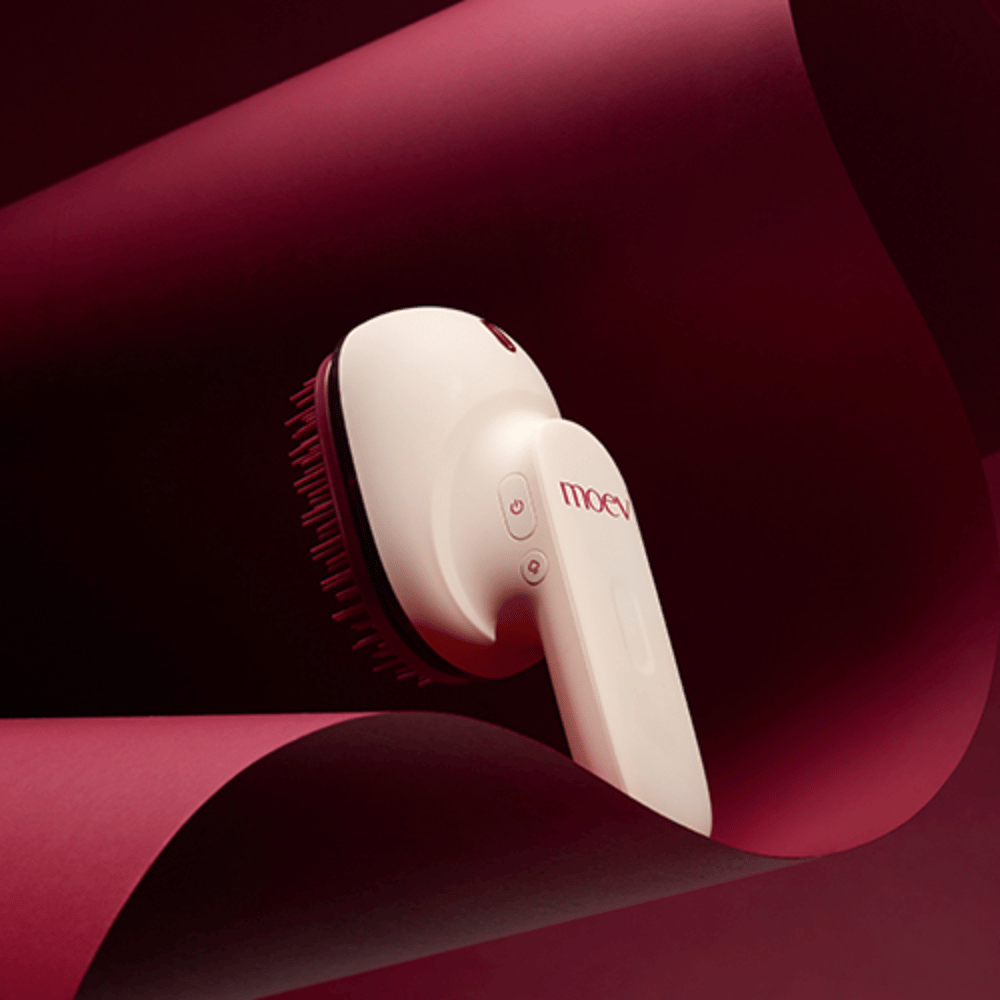 MOEV Hair Steamer Pro w eleganckim designie na czerwonym tle. Innowacyjna szczotka do pielęgnacji włosów, która wykorzystuje parę i ciepło, aby nadać blask, miękkość i wzmocnić zdrowie włosów.