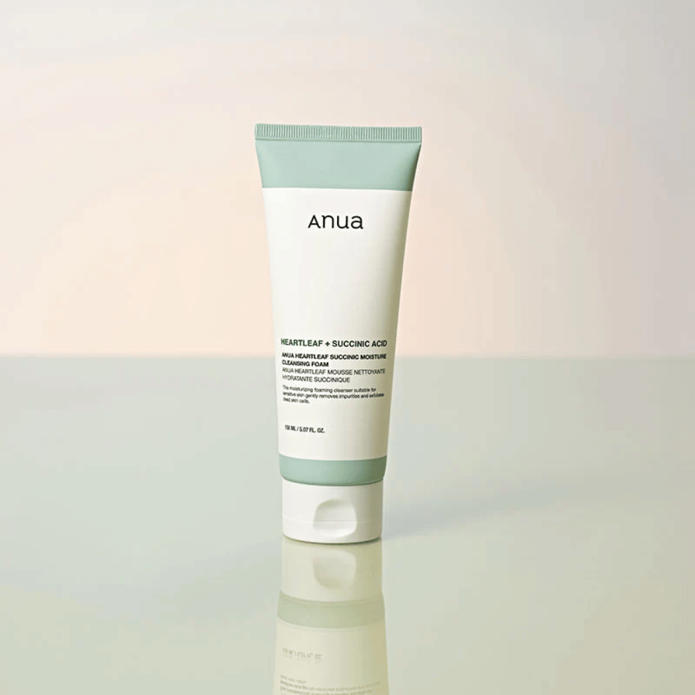Samodzielne zdjęcie produktu Anua Heartleaf + Succinic Acid Moisture Cleansing Foam. Produkt jest pokazany w pozycji stojącej na odbijającej światło powierzchni, która wyraźnie podkreśla design opakowania i elegancką estetykę marki.