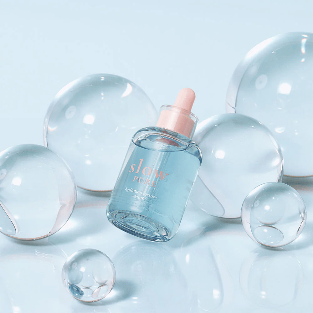 Slow Pure Hydration Texture Serum umieszczony wśród przezroczystych bąbelków, symbol intensywnego nawilżenia.