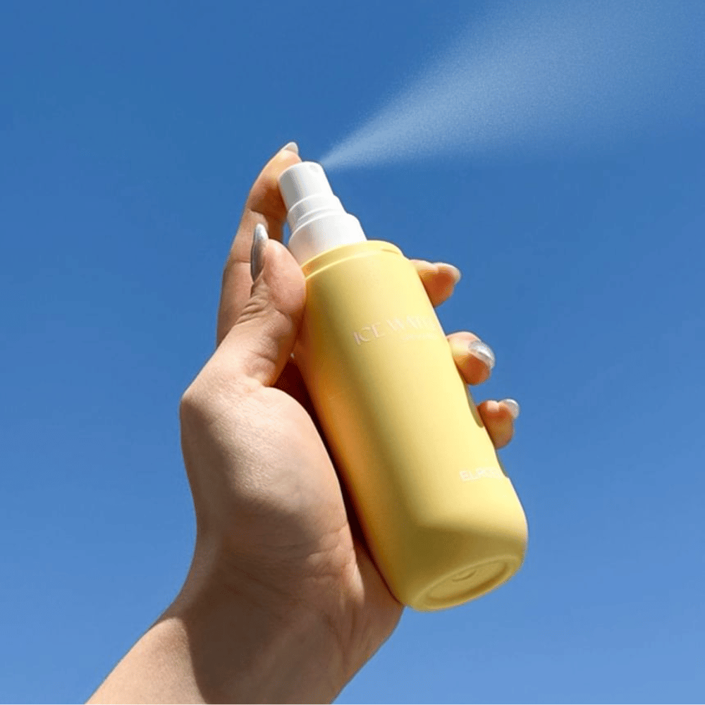 ELROEL Ice Water Sun Mist SPF 40 PA+++ mgiełka przeciwsłoneczna rozpylana z butelki na tle błękitnego nieba, lekka ochrona przeciwsłoneczna, która nawilża i odświeża skórę