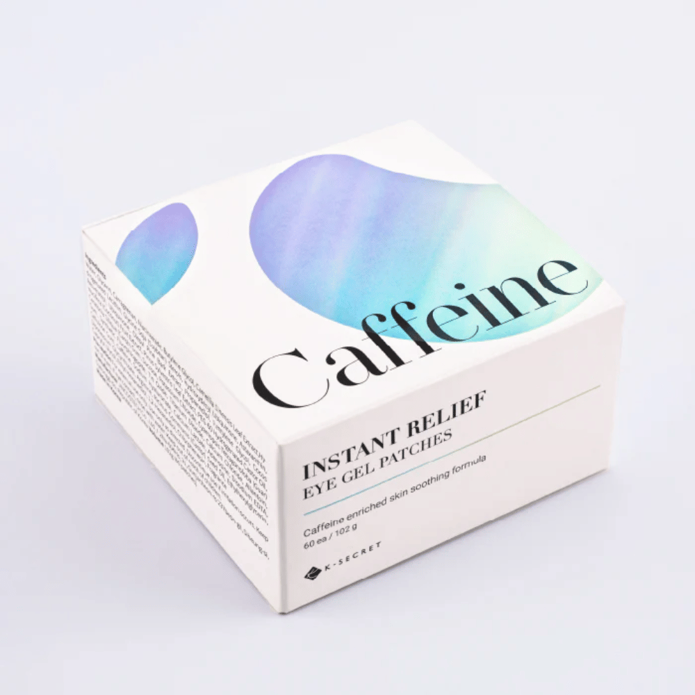 Opakowanie K-Secret Instant Relief Eye Gel Patches z kofeiną w białym wzorze z niebieskimi i zielonymi tonami.