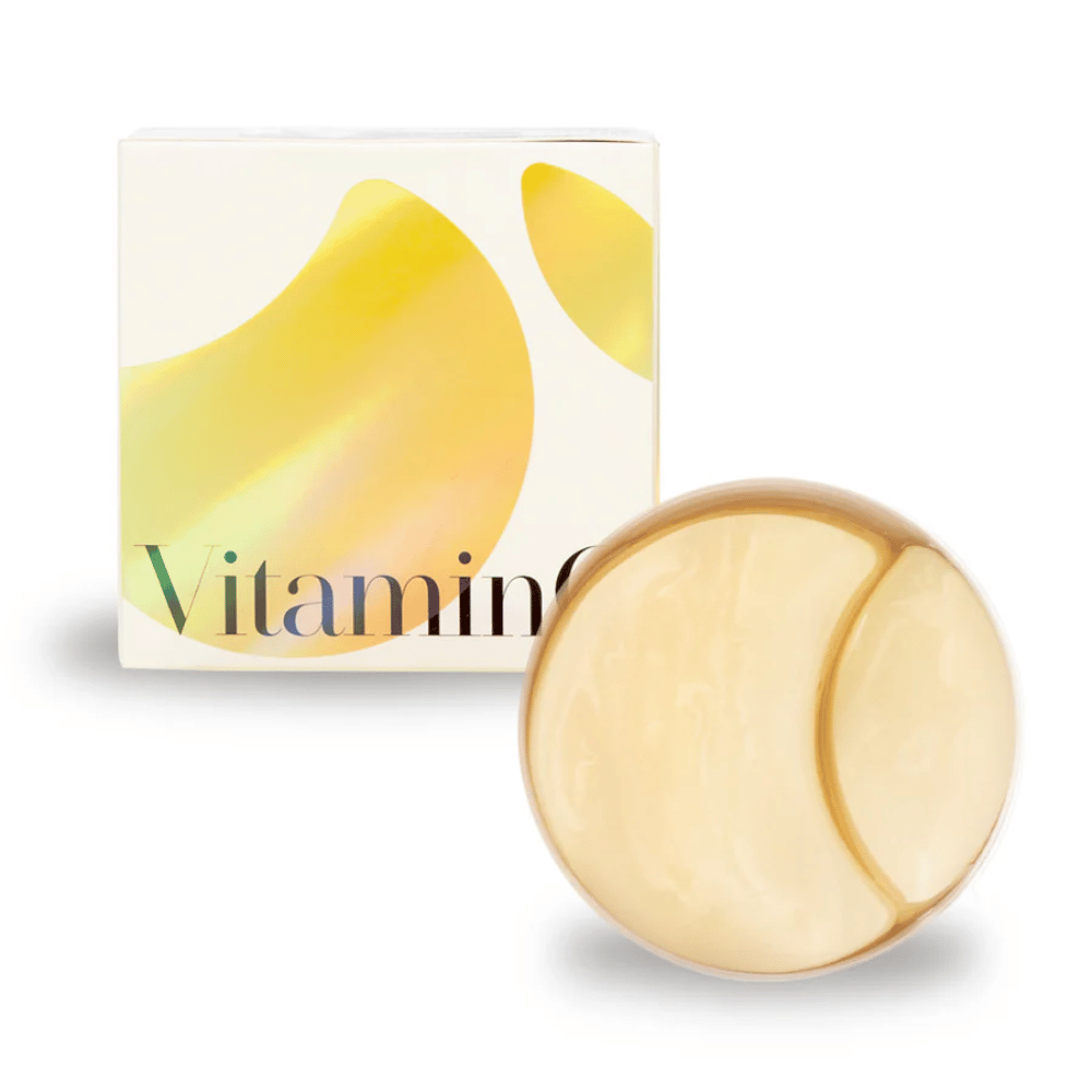 K-Secret Extra Illuminating Eye Gel Patches z witaminą C w złocistej hydrożelowej formie, słoik i opakowanie w tle.