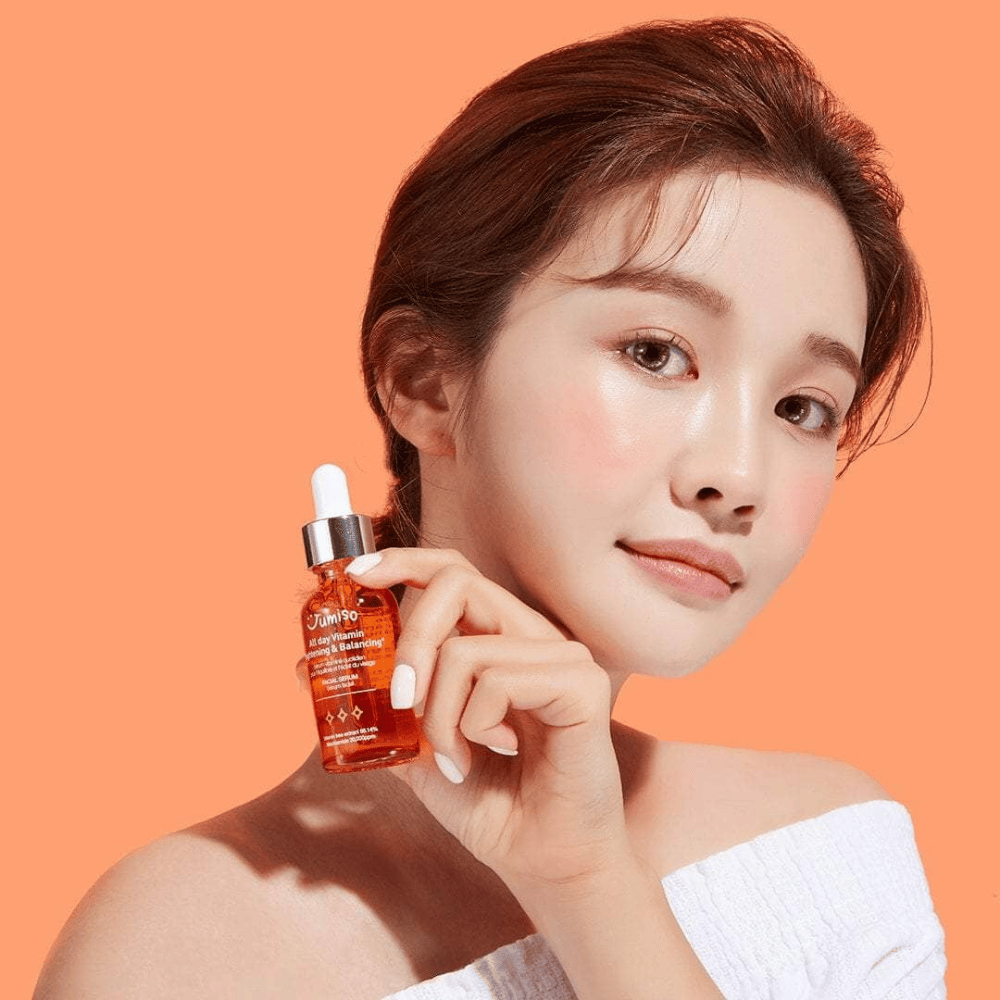 Kobieta trzymająca butelkę JUMISO All Day Vitamin Brightening & Balancing Facial Serum 30ml.