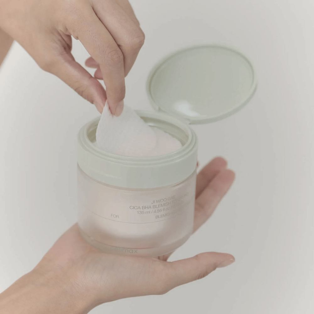 Ręka wyciąga płatek tonizujący ze słoika Celimax Ji Woo Gae Cica BHA Blemish Toner Pad, idealny dla zanieczyszczonej skóry.