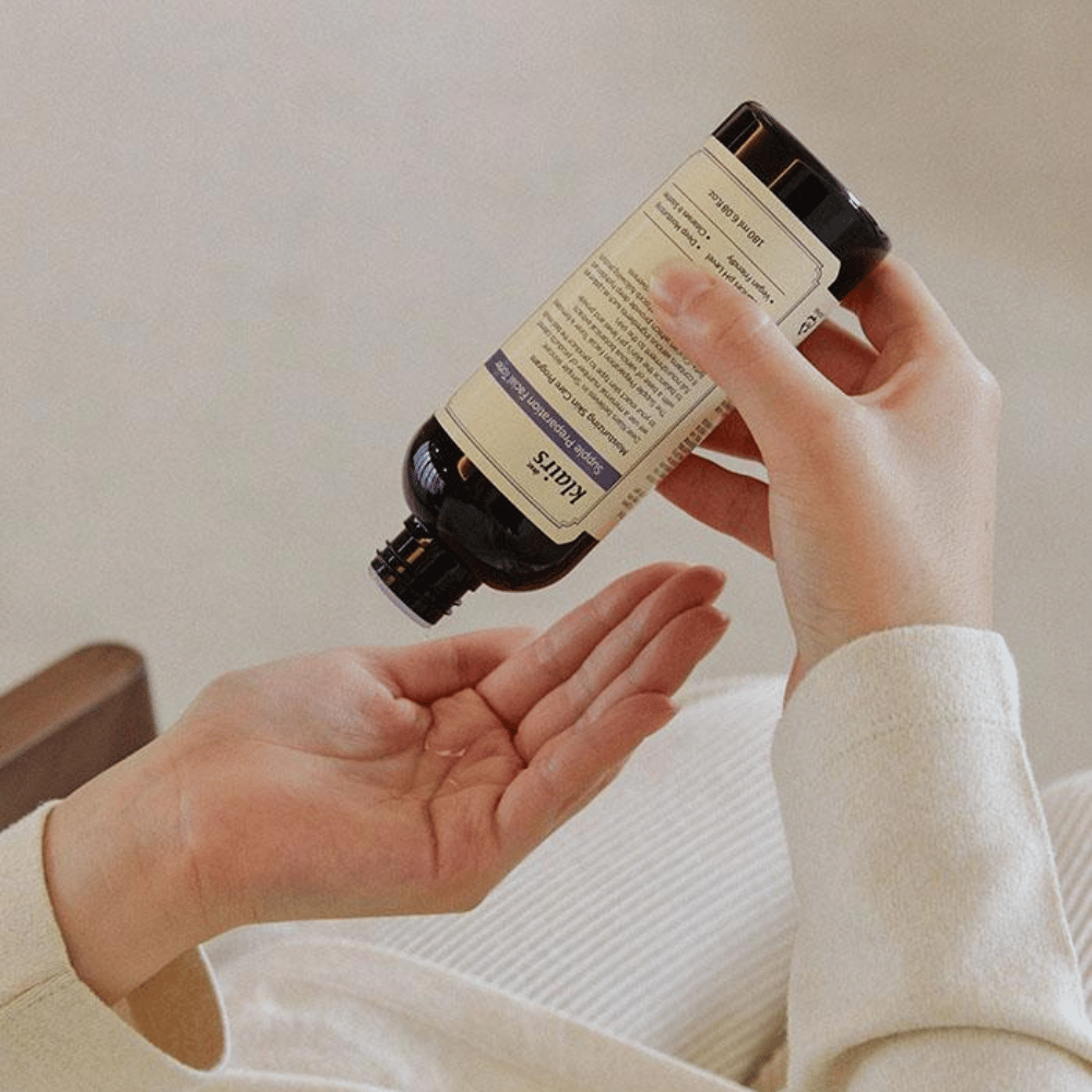 Osoba trzyma butelkę Klairs Supple Preparation Facial Toner do góry nogami nad ręką, gotowa do dozowania produktu.