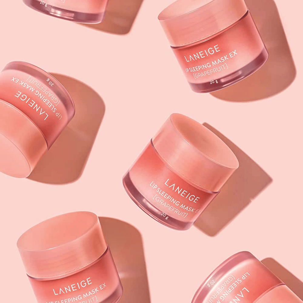 Cztery słoiki LANEIGE Lip Sleeping Mask Grejpfrut 20g na różowym tle, promuje grejpfrut i nawilżenie.
