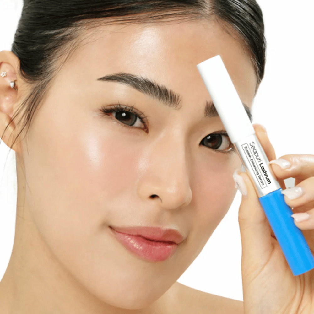 Kobieta trzyma Seapuri Lashrum Eyelash Enhancing Serum. Odżywcze serum do rzęs, które wzmacnia i definiuje rzęsy.