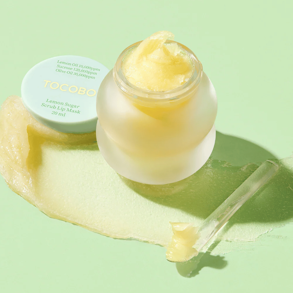 Otwarty słoik z Tocobo Lemon Sugar Scrub Lip Mask na zielonym tle, z wyraźnie widoczną zawartością.