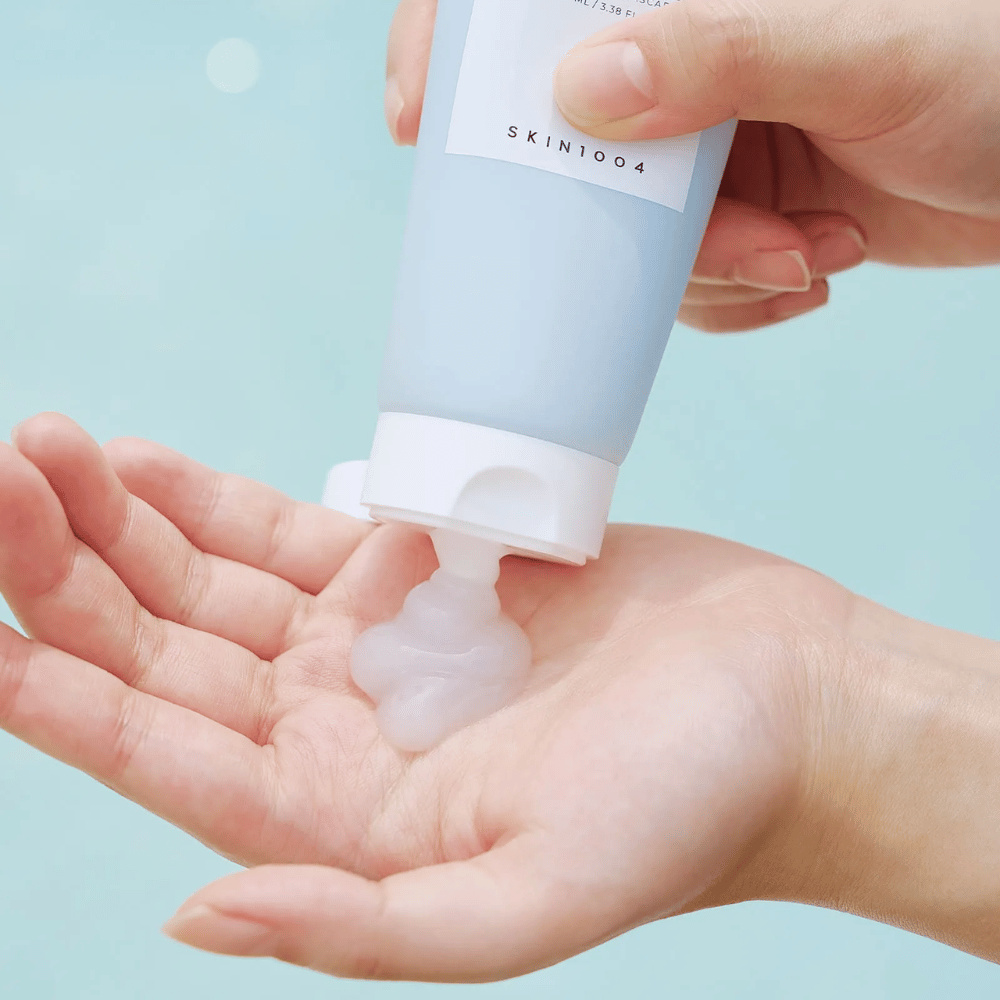 Obrazek przedstawia kogoś, kto wyciska przezroczystą żelową substancję z tubki oznaczonej "SKIN1004 Madagascar Centella Hyalu-Cica Sleeping Pack" zawierającej 100 ml produktu.