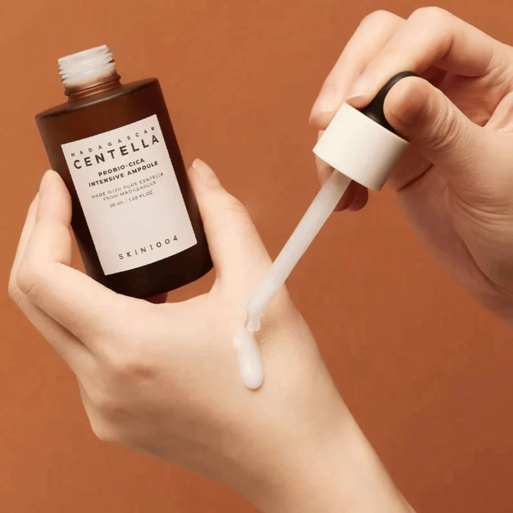 Ręce używające pipety do dozowania "Madagascar Centella Probio-Cica Intensive Ampoule" od SKIN1004.
