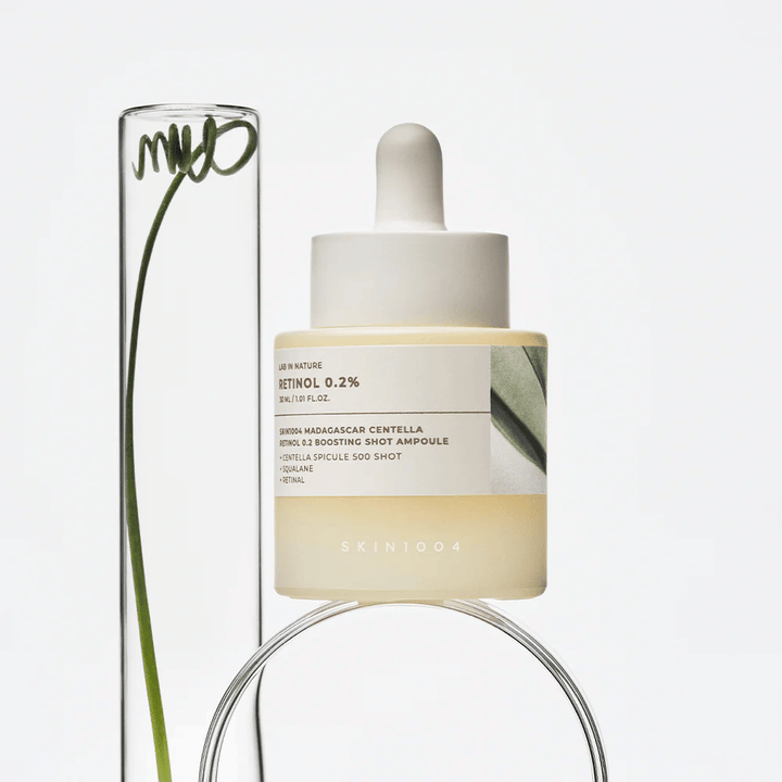 SKIN1004 Madagascar Centella Retinol 0.2 Boosting Shot Ampoule na zdjęciu lifestyle z elementami botanicznymi – serum do twarzy wspierające odnowę skóry i wzmacniające barierę skórną.
