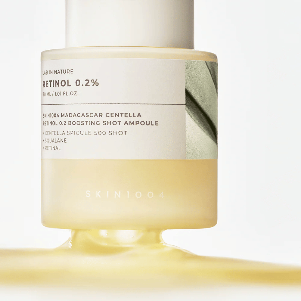 Zbliżenie na SKIN1004 Madagascar Centella Retinol 0.2 Boosting Shot Ampoule pokazujące jasnożółtą, jedwabistą konsystencję serum z retinolem do nocnej odnowy skóry.