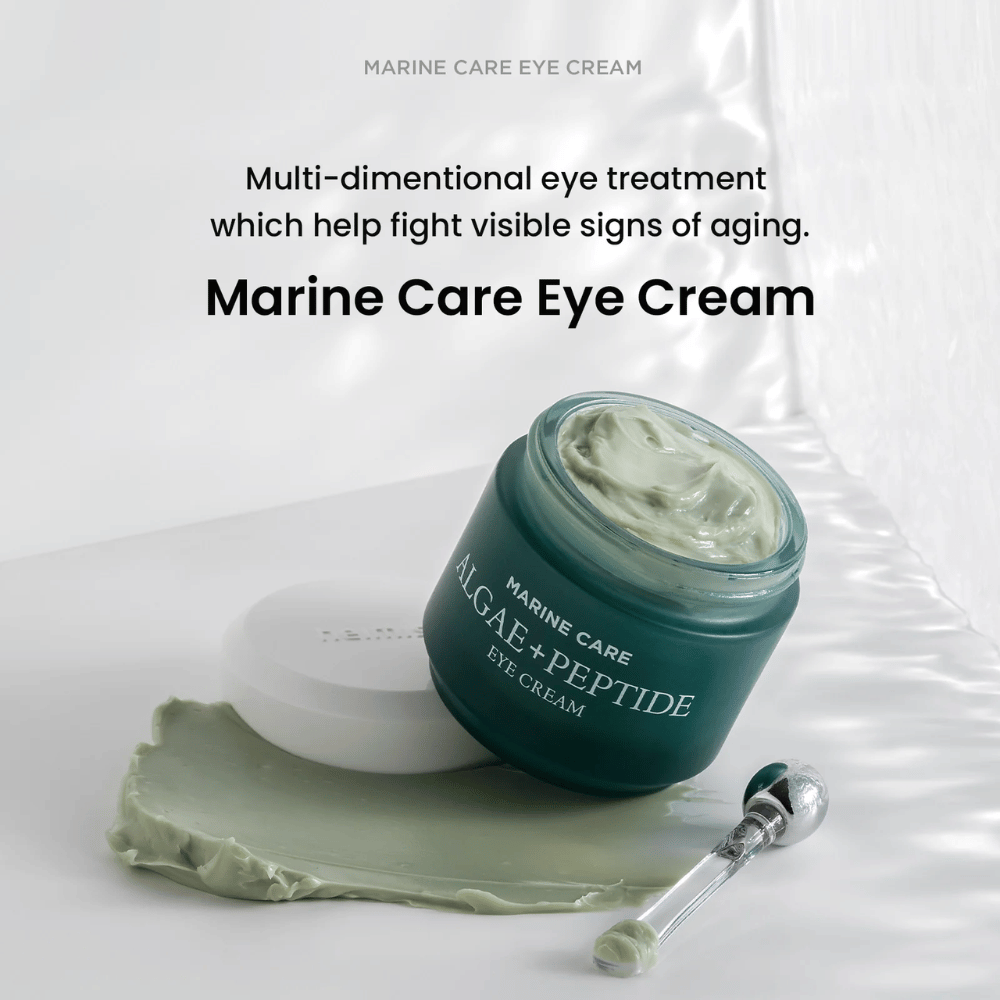 Heimish Marine Care Algae + Peptide Eye Cream w otwartym słoiku z zielonkawym kremem. Krem jest rozprowadzony obok słoika, a aplikator leży obok. Produkt zwalcza oznaki starzenia i zapewnia intensywne nawilżenie.