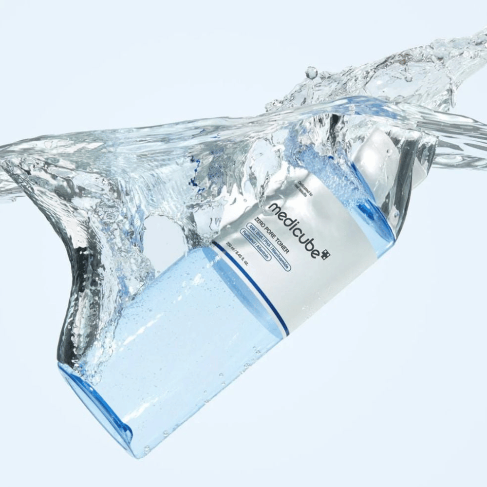 Medicube Zero Pore Toner 250 ml, złuszczający tonik do twarzy z AHA, BHA i PHA. Przezroczysta niebieska butelka otoczona dużym rozpryskiem wody.