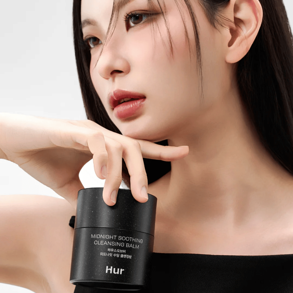 Modelka trzyma Jak Midnight Soothing Cleansing Balm. Koreański balsam oczyszczający, który skutecznie usuwa makijaż i oczyszcza skórę bez podrażnień.