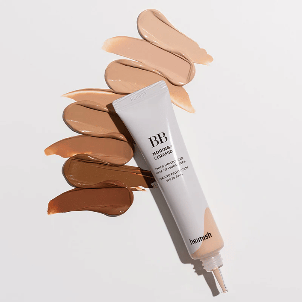 Heimish Moringa Ceramide BB Cream otoczony kilkoma próbkami odcieni w różnych tonacjach skóry. Obraz pokazuje szeroką gamę kolorystyczną produktu oraz kremową konsystencję, która zapewnia naturalne krycie i wyrównany koloryt skóry.