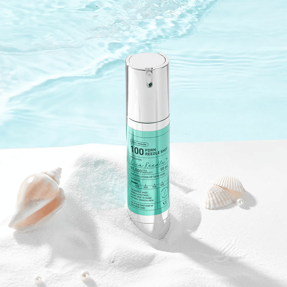 VT Cosmetics PDRN Reedle Shot 100 produkt umieszczony w piaszczystym otoczeniu o morskim charakterze, symbolizującym nawilżenie, działanie kojące i poprawę kondycji skóry