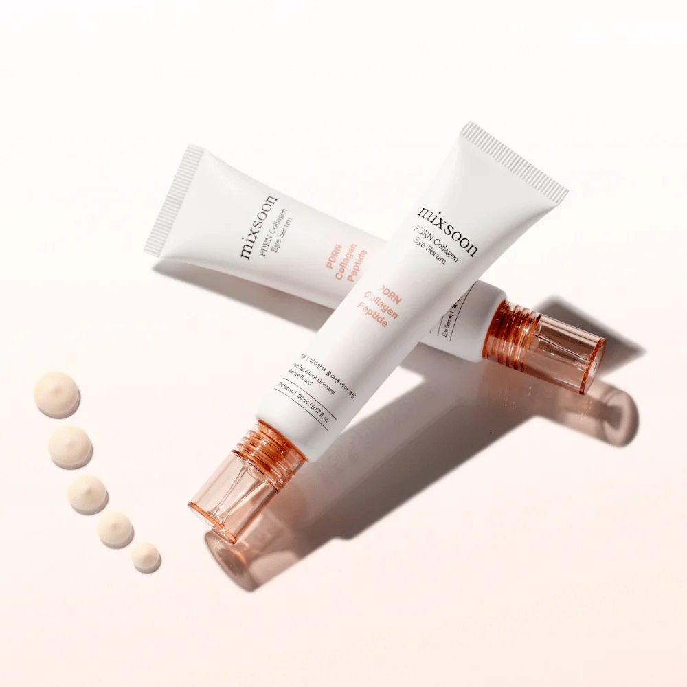 Dwie tubki Mixsoon PDRN Collagen Eye Serum leżą skrzyżowane z małymi kroplami serum. Lekka kuracja pod oczy, która nawilża i wygładza linie.
