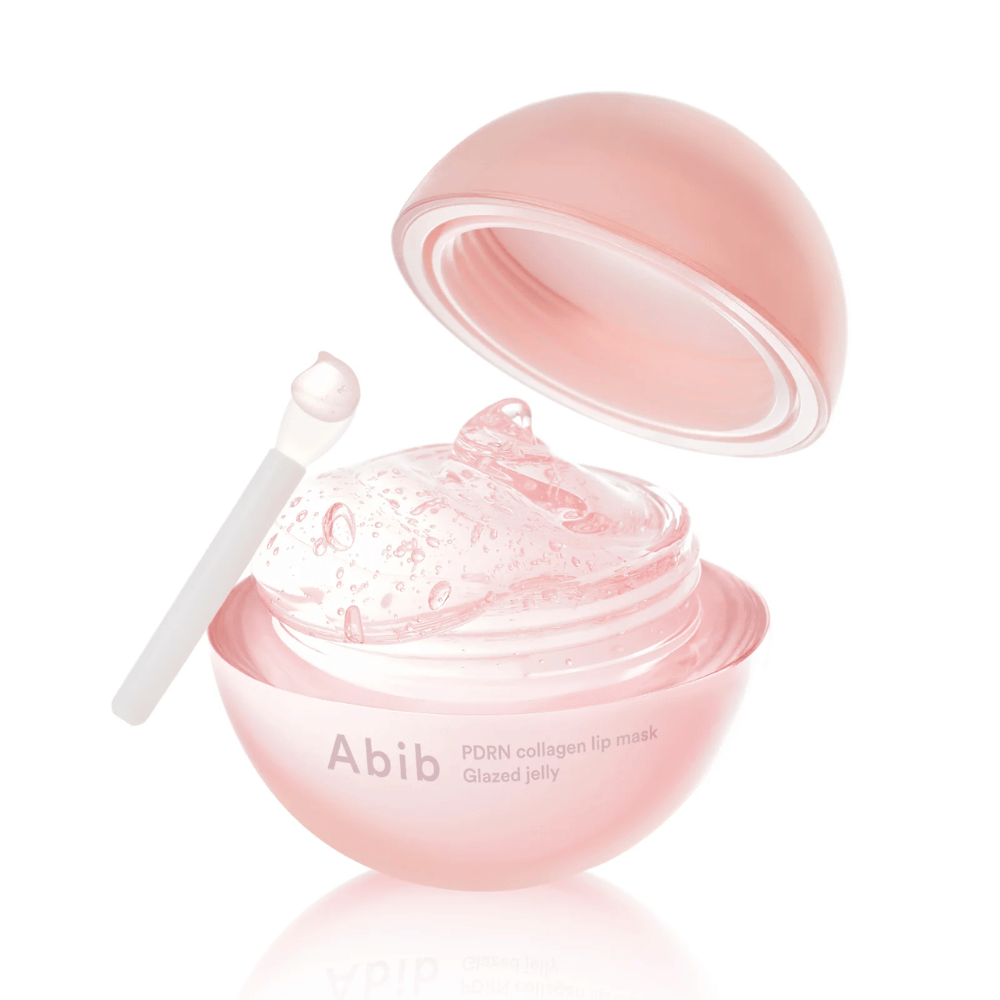 Różowy okrągły słoik z Abib PDRN Collagen Lip Mask Glazed Jelly, otwarty z pokrywką przechyloną do tyłu. Przezroczysty żel z pęcherzykami powietrza widoczny w słoiku wraz z małą szpatułką.
