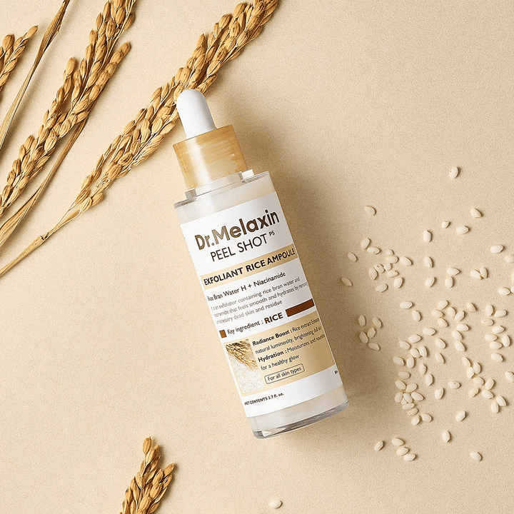 Dr.Melaxin Peel Shot Rice Ampoule leżąca na piaskowym tle z ryżem i kłosem, złuszczająca ampułka do twarzy, która łączy łagodne złuszczanie z intensywnym nawilżeniem.