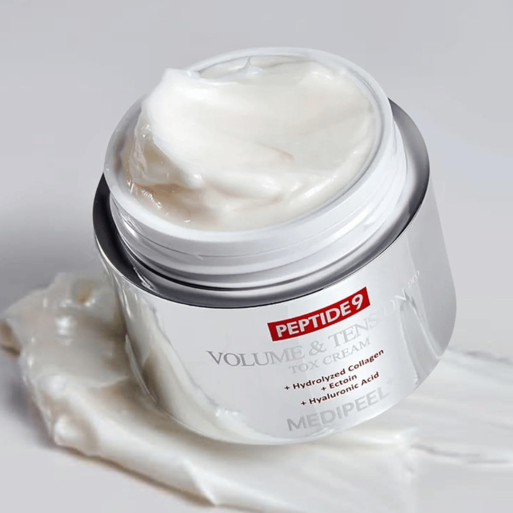 Zbliżenie na MEDI-PEEL Peptide 9 Volume & Tension Tox Cream. Bogaty krem zawiera hydrolizowany kolagen, ektoinę i kwas hialuronowy dla jędrniejszej i nawilżonej skóry.