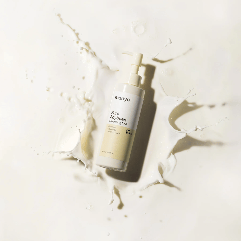 1. Ma:nyo Pure Soybean Cleansing Milk – delikatne mleczko oczyszczające z soją w butelce z pompką otoczonej rozpryskami mleka na jasnym tle