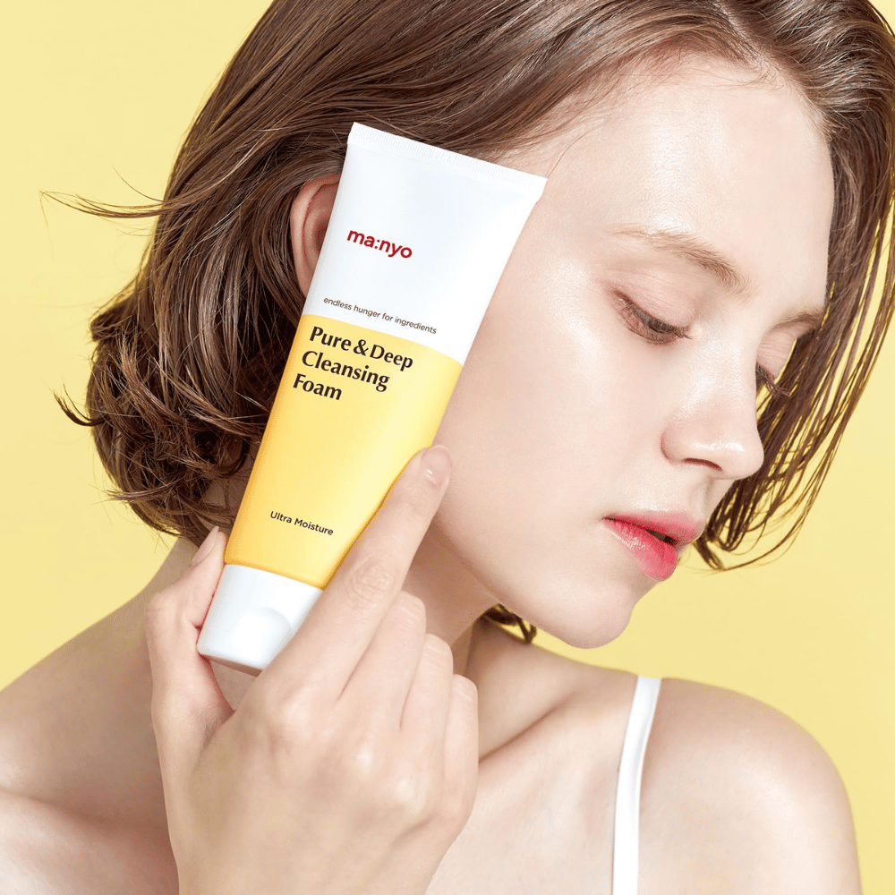 Kobieta z zdrową, nawilżoną skórą trzyma Ma:nyo Pure & Deep Cleansing Foam – delikatny środek do mycia twarzy, który dodaje blasku i równowagi dzięki naturalnym składnikom.