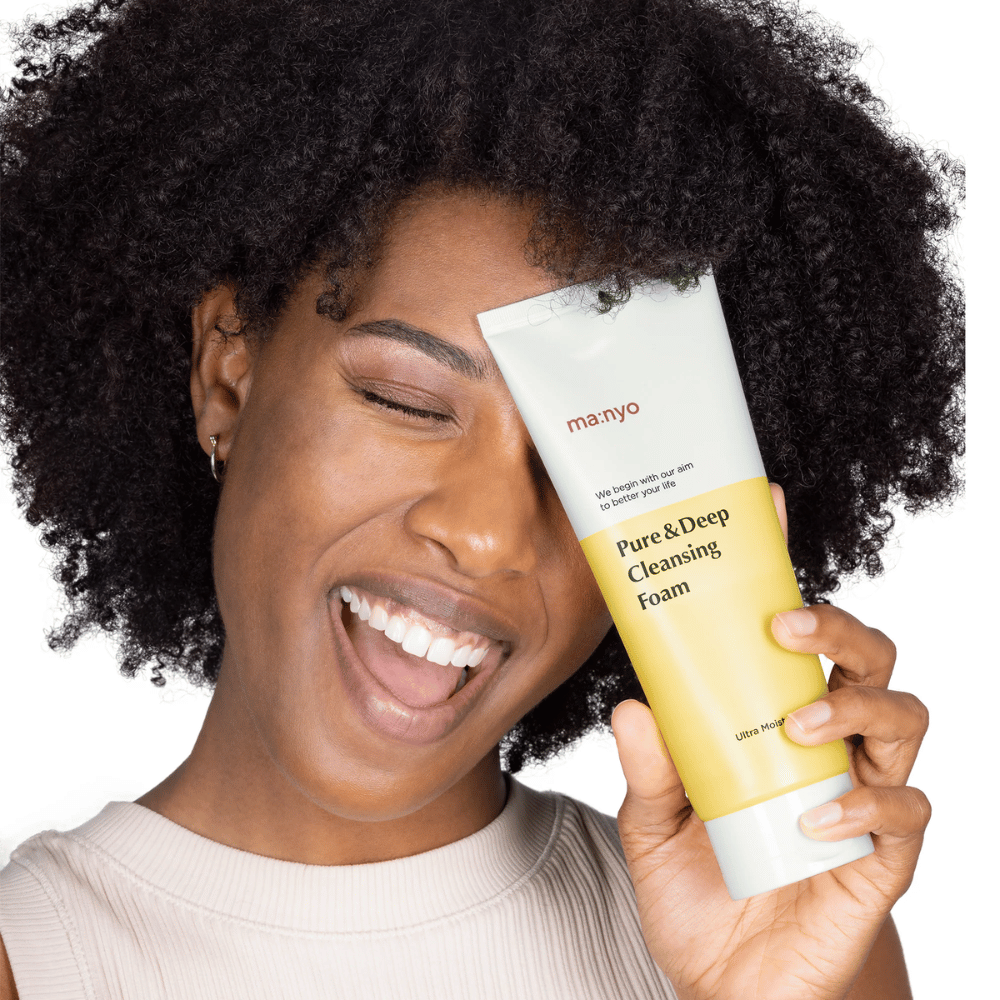 Kobieta z kręconymi włosami trzyma Ma:nyo Pure & Deep Cleansing Foam – delikatny koreański środek czyszczący, który skutecznie usuwa brud i makijaż bez wysuszania skóry.