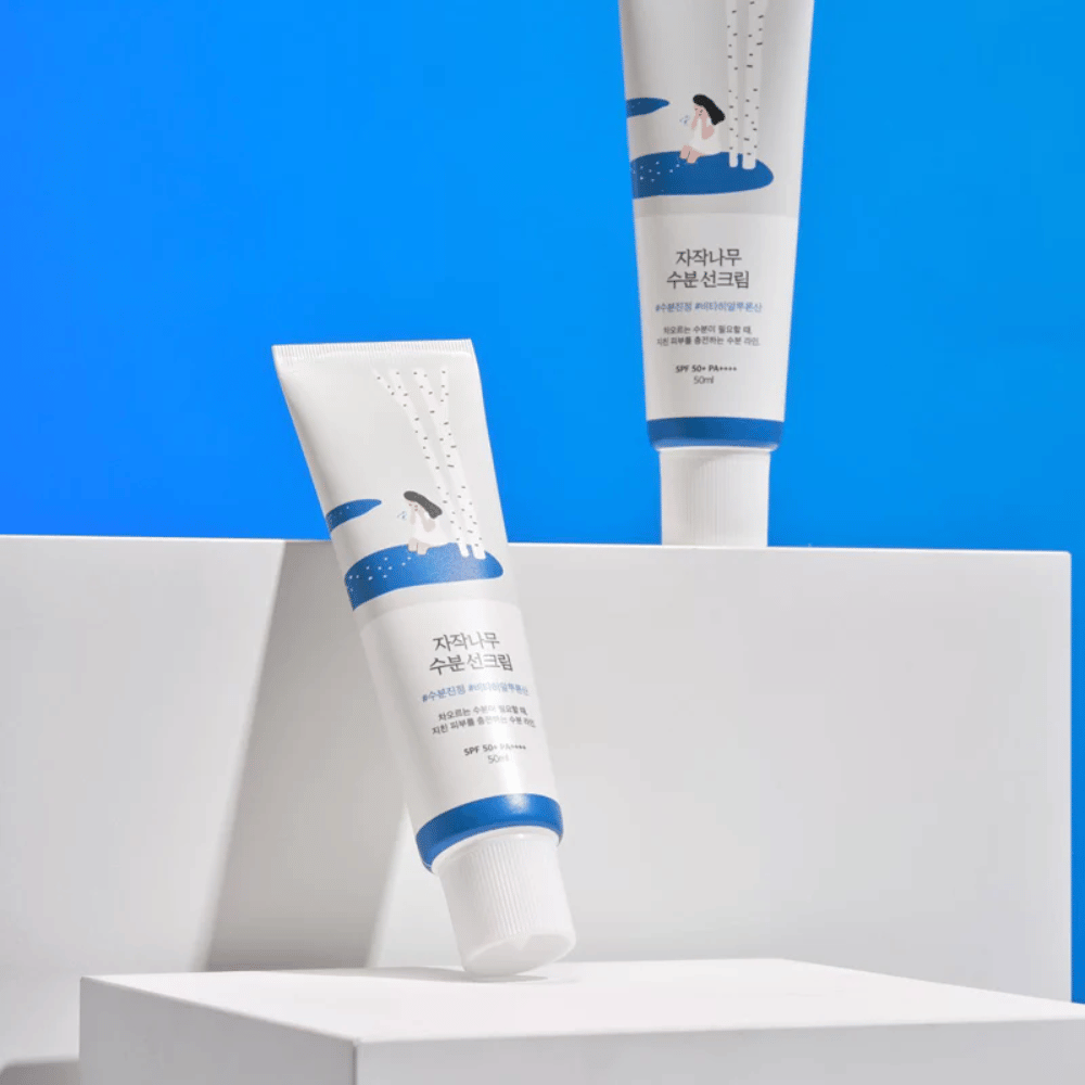 Dwie tuby z Round Lab Birch Juice Moisturizing Sunscreen SPF50+ PA++++ 50ml na niebieskim tle.