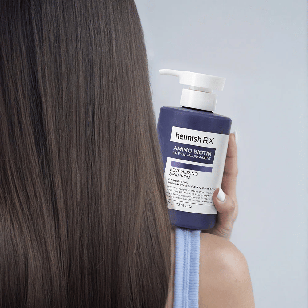 Heimish RX Amino Biotin Revitalizing Shampoo trzymane w dłoni przy długich, lśniących włosach – pokazuje efekt intensywnego odżywienia i nawilżenia dla suchych włosów.