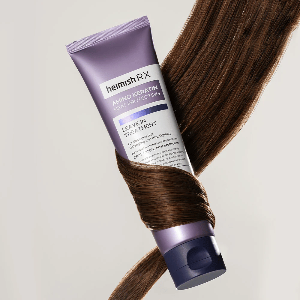 Heimish RX Amino Keratin Leave-In Treatment – odżywcza, chroniąca przed ciepłem kuracja do włosów otoczona lśniącymi włosami, symbolizuje wzmacniający i nawilżający efekt dla zniszczonych włosów.