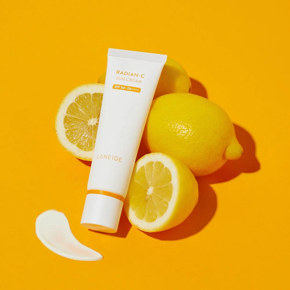 LANEIGE Radian-C Sun Cream SPF 50+ PA++++ z cytrynami i odrobiną kremu przeciwsłonecznego na kolorowym żółtym tle.