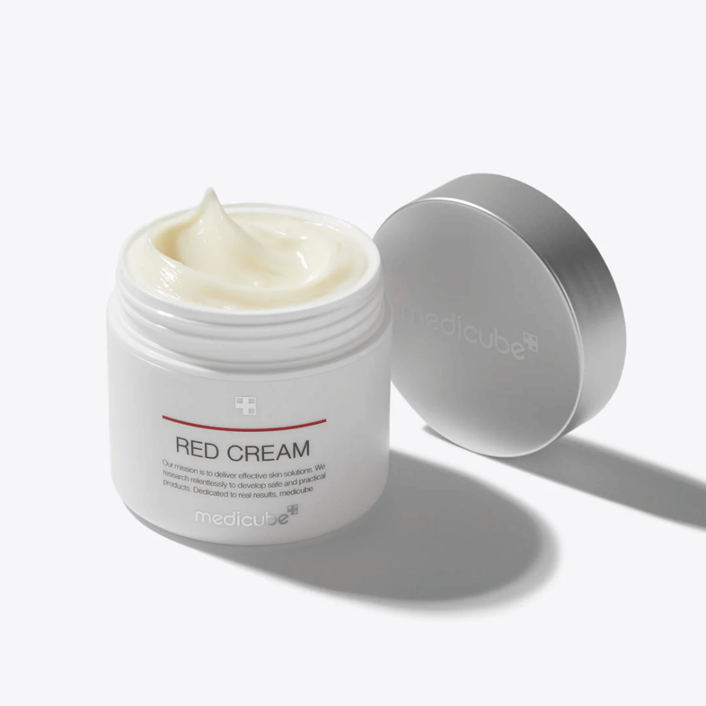 Otwarty słoik z medicube Red Cream 50ml – jasnożółty krem do twarzy w białym opakowaniu ze srebrną pokrywką, opracowany dla skóry skłonnej do trądziku.