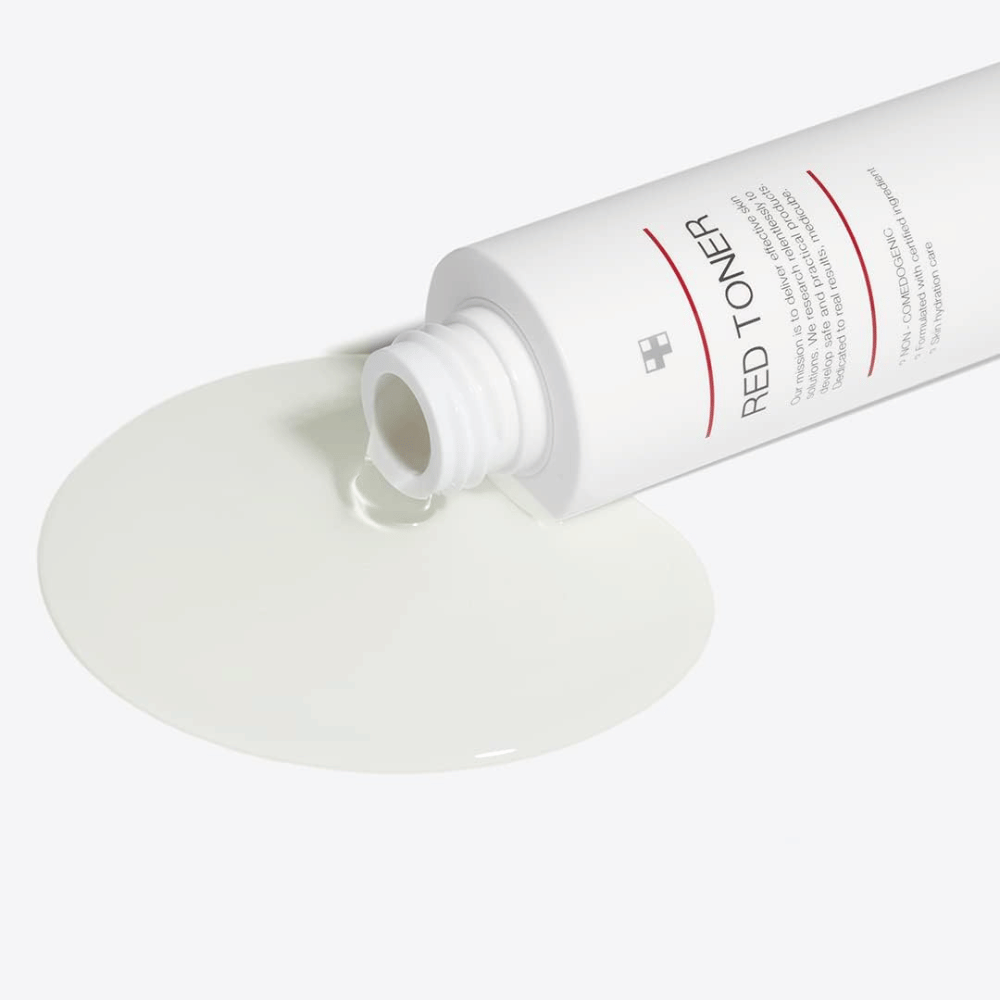 Otwarta butelka z medicube Red Toner wylewana na białą powierzchnię – pokazuje lekką i płynną konsystencję produktu.