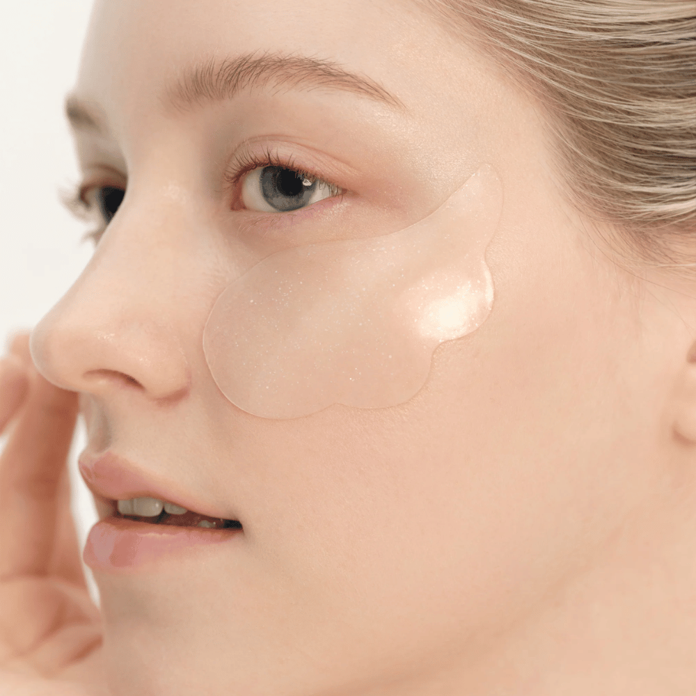 Zbliżenie modelki nakładającej Beauty of Joseon plasterek pod oczy dla nawilżenia, blasku i efektu ujędrnienia.