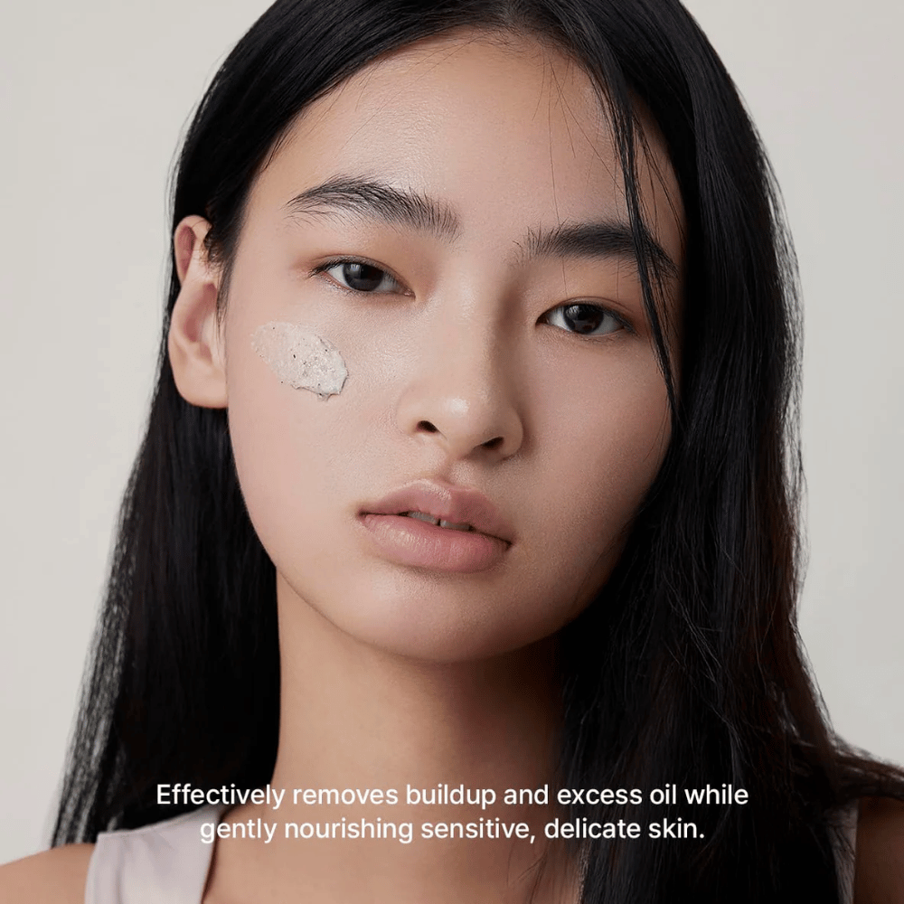 Model z Arencia Rice + LHA Pore Control Rice Cake Cleanser nałożonym na policzek, łagodny środek do oczyszczania twarzy, który skutecznie usuwa brud i nadmiar sebum, nie wysuszając skóry.