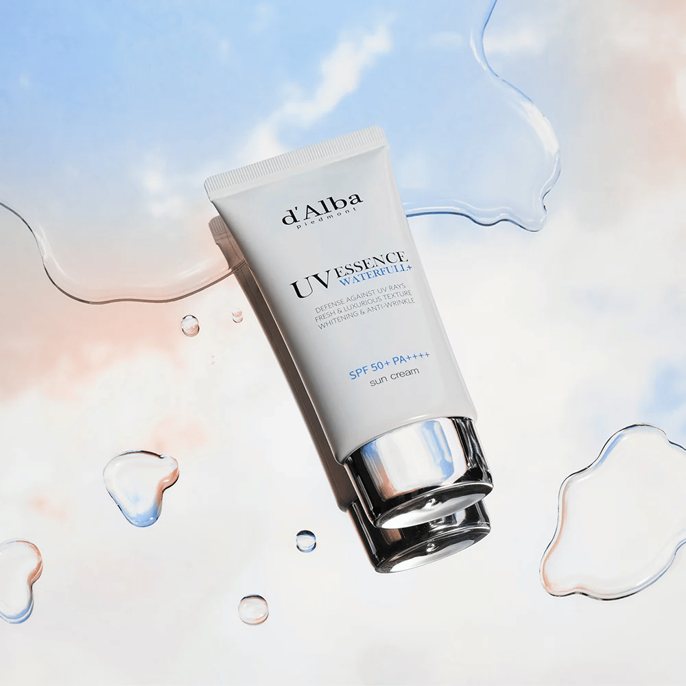 Zdjęcie produktu d'Alba UV Essence Waterfull+ Sun Cream z SPF 50+ PA++++, umieszczone na tle z rozpryskami wody i błękitnoróżowym niebem – symbolizuje lekką i nawilżającą ochronę przeciwsłoneczną.