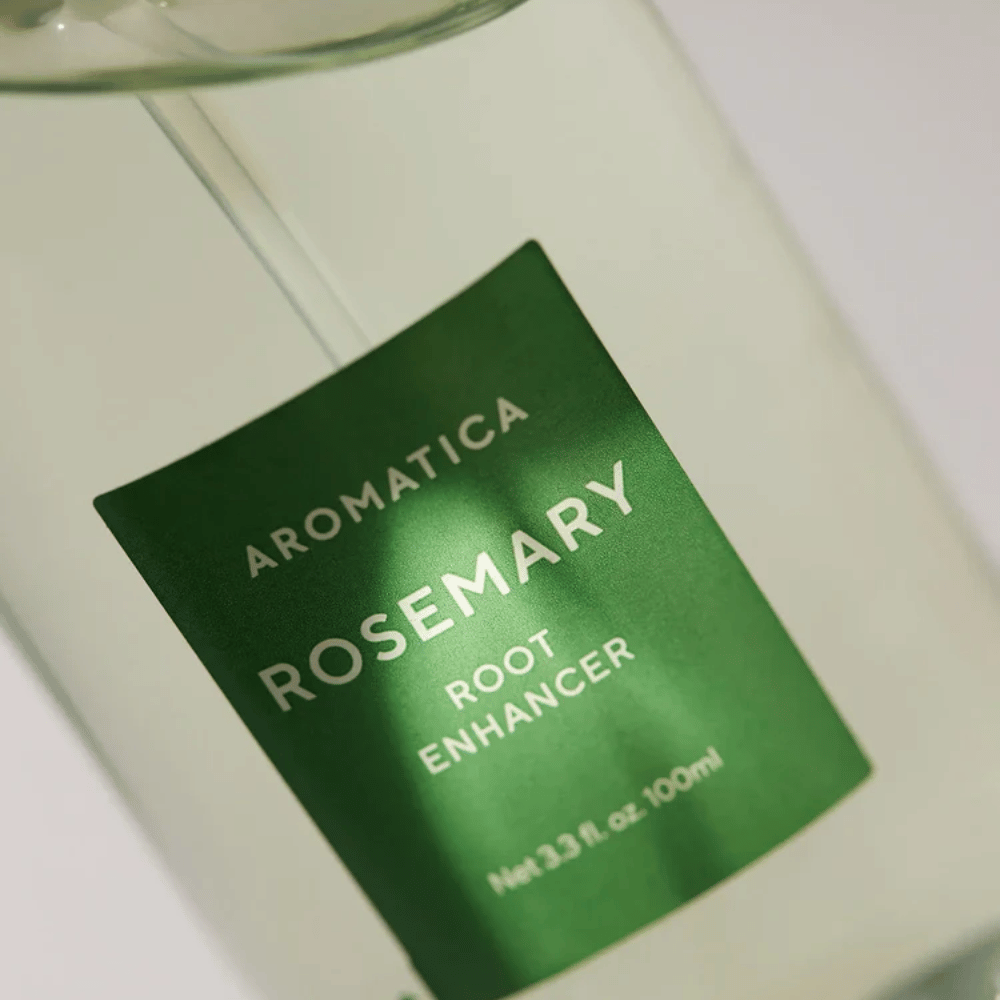 Zbliżenie etykiety na AROMATICA Rosemary Root Enhancer. Zielona etykieta i przezroczysta butelka podkreślają czysty i minimalistyczny wygląd produktu.
