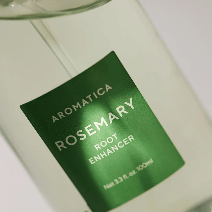 Zbliżenie etykiety na AROMATICA Rosemary Root Enhancer. Zielona etykieta i przezroczysta butelka podkreślają czysty i minimalistyczny wygląd produktu.