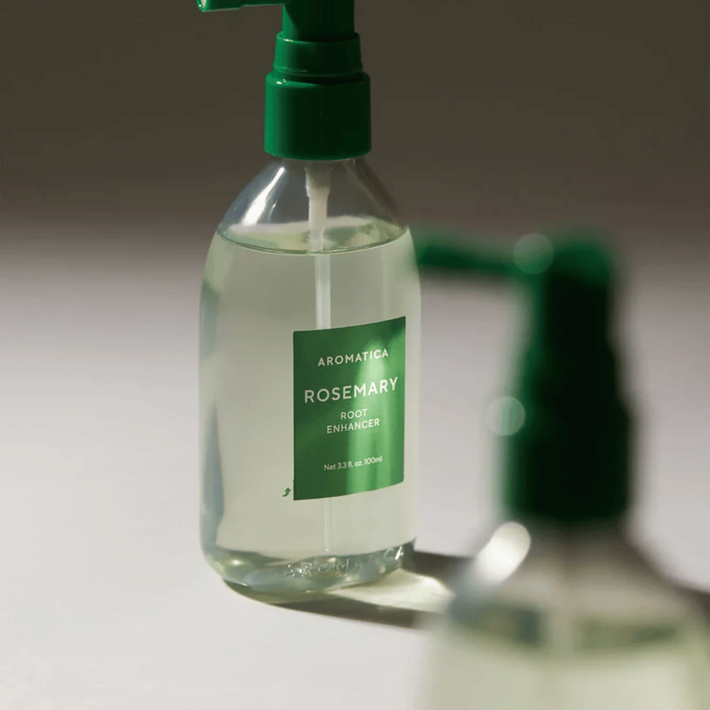 Zbliżenie na AROMATICA Rosemary Root Enhancer z zielonym aplikatorem z dyszą. Obraz koncentruje się na designie butelki i precyzyjnej aplikacji bezpośrednio na skórę głowy.