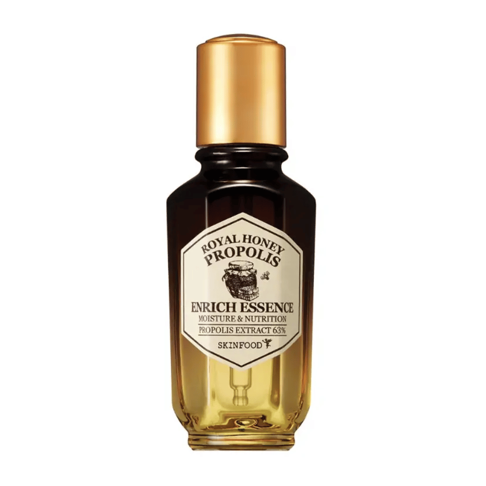 Obraz szklanej butelki z ciemnym płynem i złotym wieczkiem. Na etykiecie butelki widnieje napis "Royal Honey Propolis Enrich Essence" następnie "Moisture & Nutrition" i "Propolis Extract 63%". Marka "Skinfood" jest również widoczna na dole etykiety.