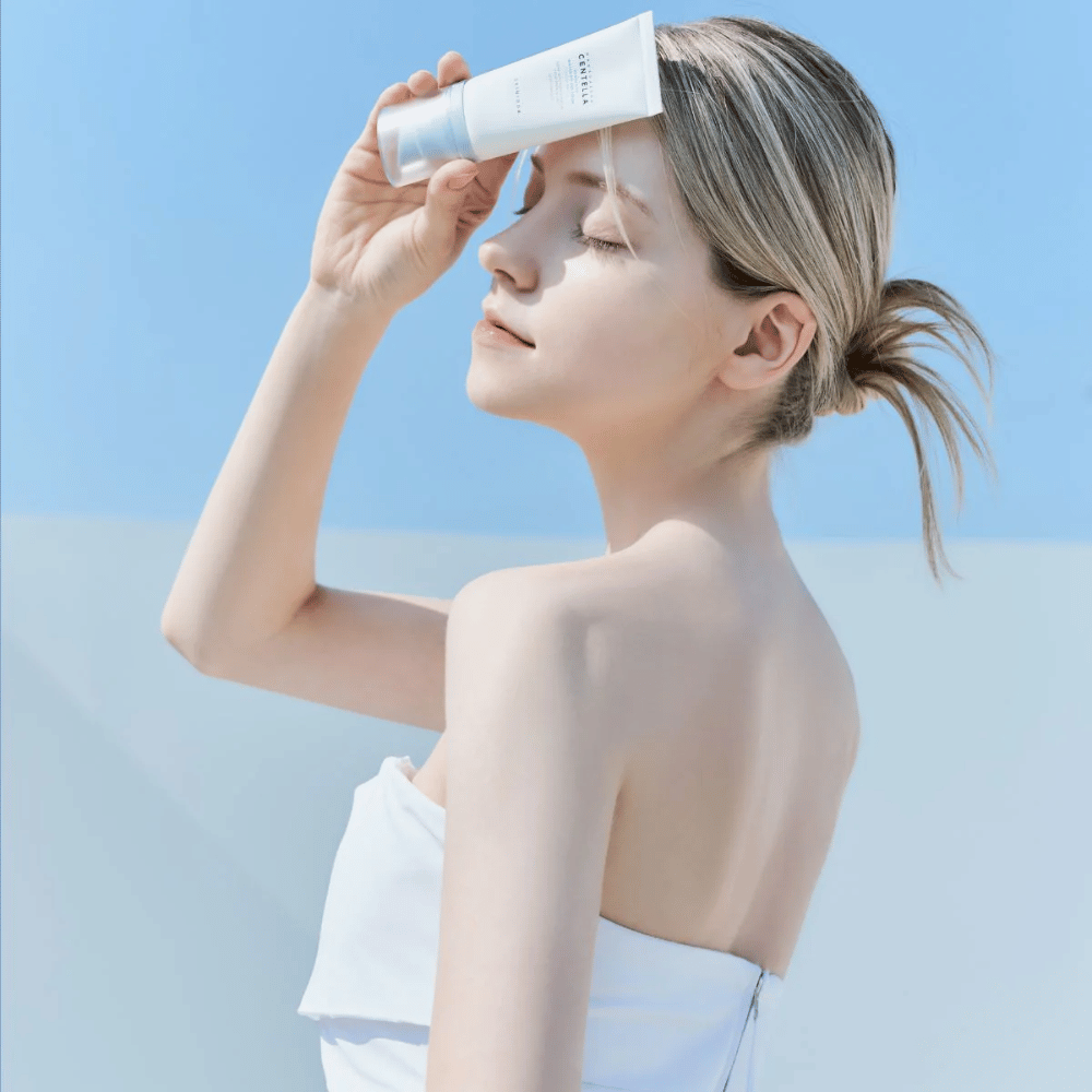 Kobieta nakłada SKIN1004 Madagascar Centella Hyalu-Cica Water-Fit Sun Serum 50ml, aby chronić twarz przed promieniowaniem UV.