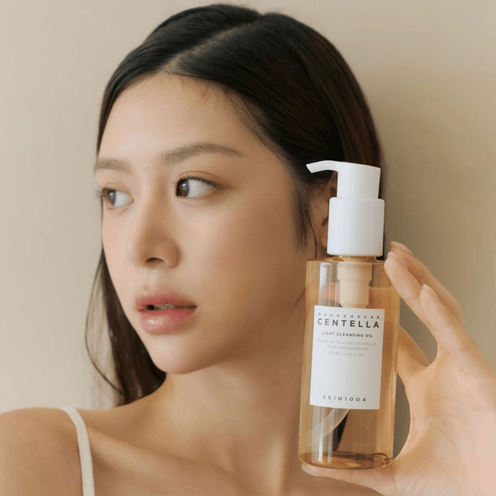 Kobieta trzymająca butelkę SKIN1004 Madagascar Centella Light Cleansing Oil 200 ml środka do oczyszczania twarzy.