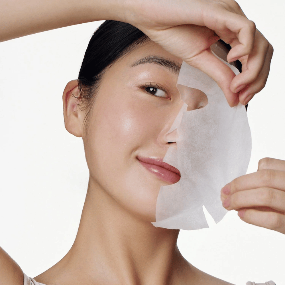Ten obraz pokazuje osobę używającą maseczki do twarzy, konkretnie "Galactomyces Glutathione Daily Mask" od Some By Mi. Maska rozjaśnia skórę i nadaje jej promienny blask, jednocześnie pielęgnując i głęboko nawilżając skórę, dzięki składnikom takim jak glutation i witamina C.