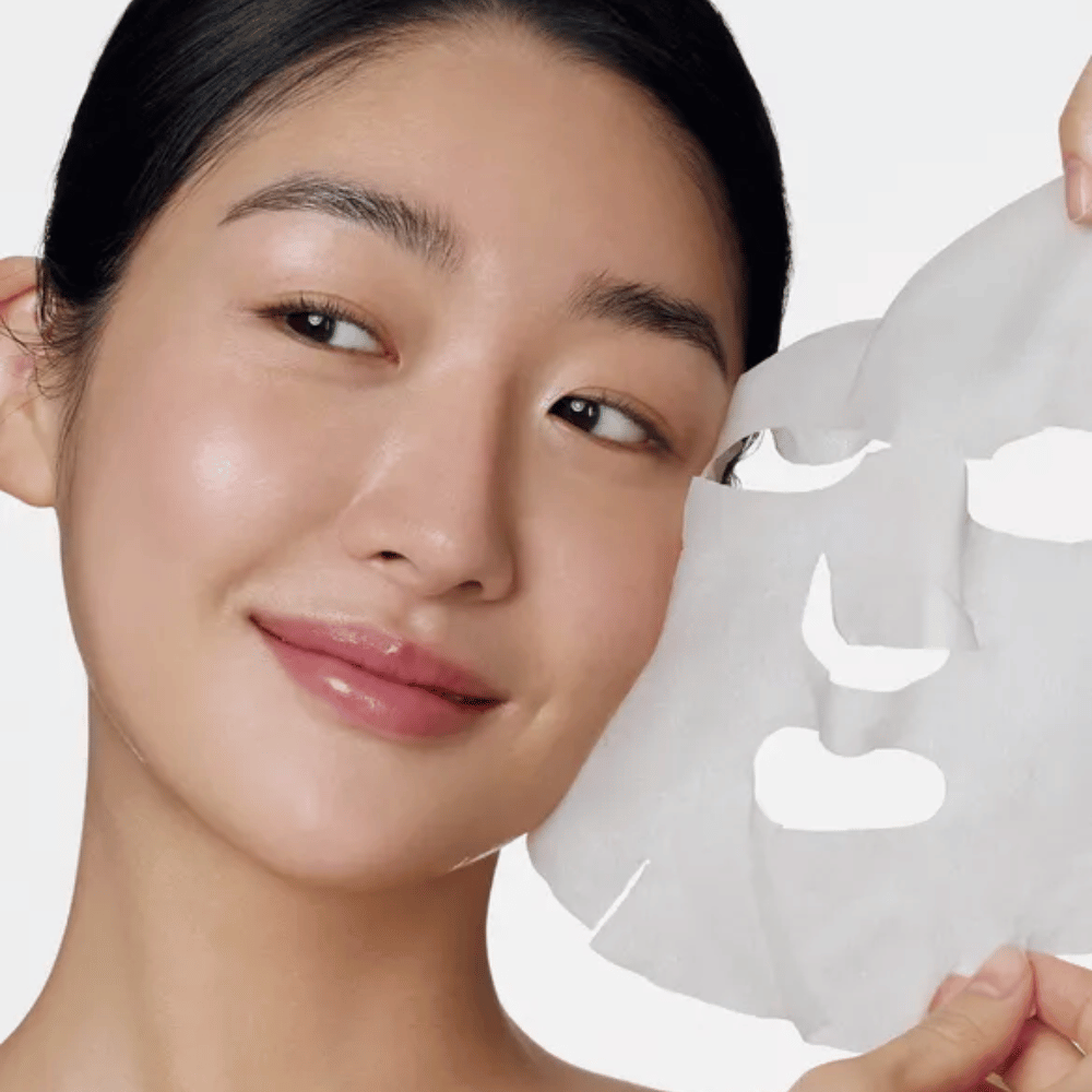 Obraz przedstawia osobę używającą maski do twarzy, konkretnie "Retinol Intense Daily Mask" z Some By Mi. Maska jest przeznaczona do codziennego użytku i zawiera retinol, aby poprawić teksturę skóry, zmniejszyć drobne linie i zapewnić bardziej jednolity koloryt skóry.