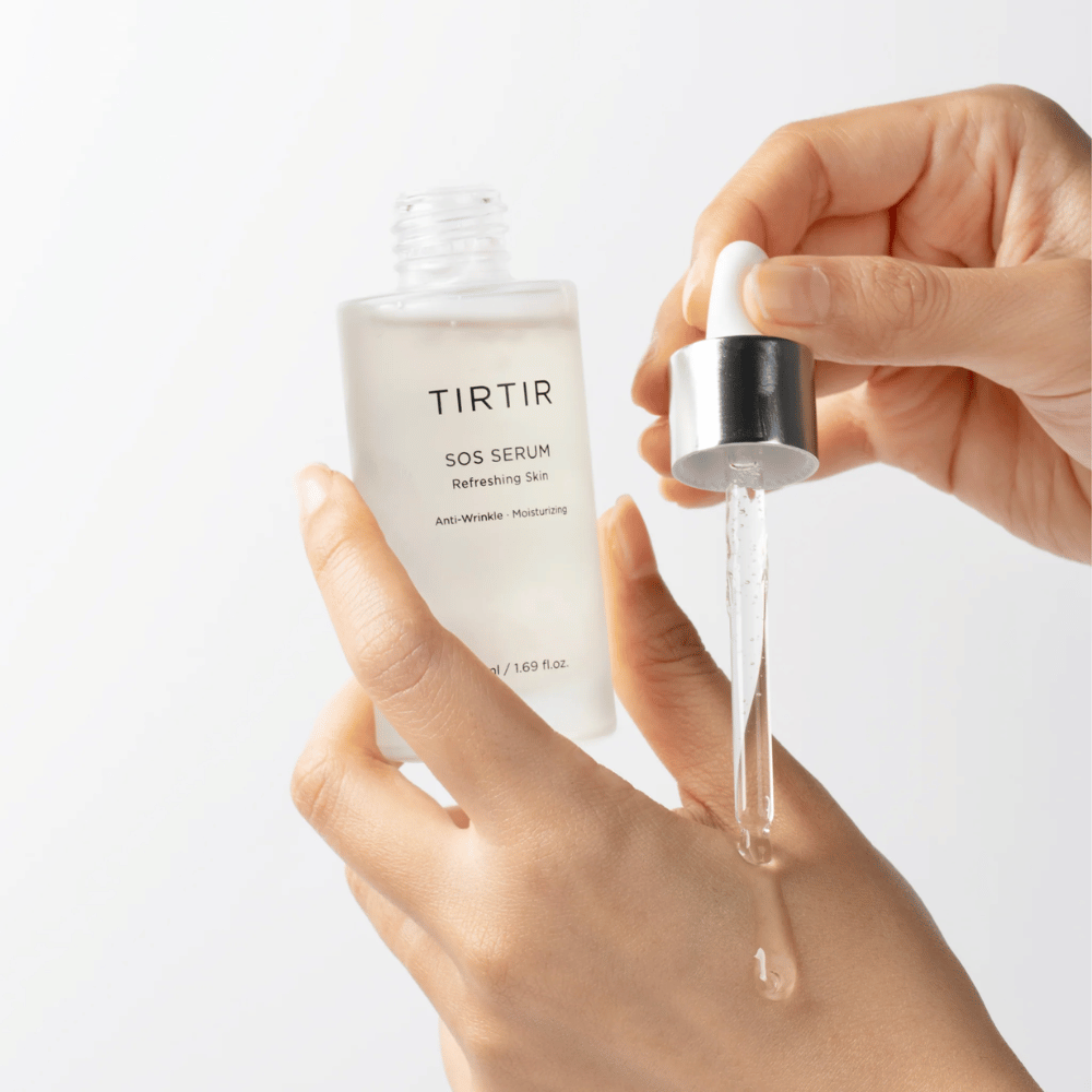 Ręce, które kapią TIRTIR SOS Serum z pipety, przeznaczone do pielęgnacji skóry.