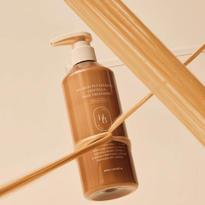 Heveblue Salmon Pullkeratin Centella Hair Treatment w brązowej butelce otoczonej pasmami włosów. Obraz podkreśla pielęgnacyjne właściwości kuracji do włosów, koncentrując się na blasku, sile i jedwabiście gładkich włosach.