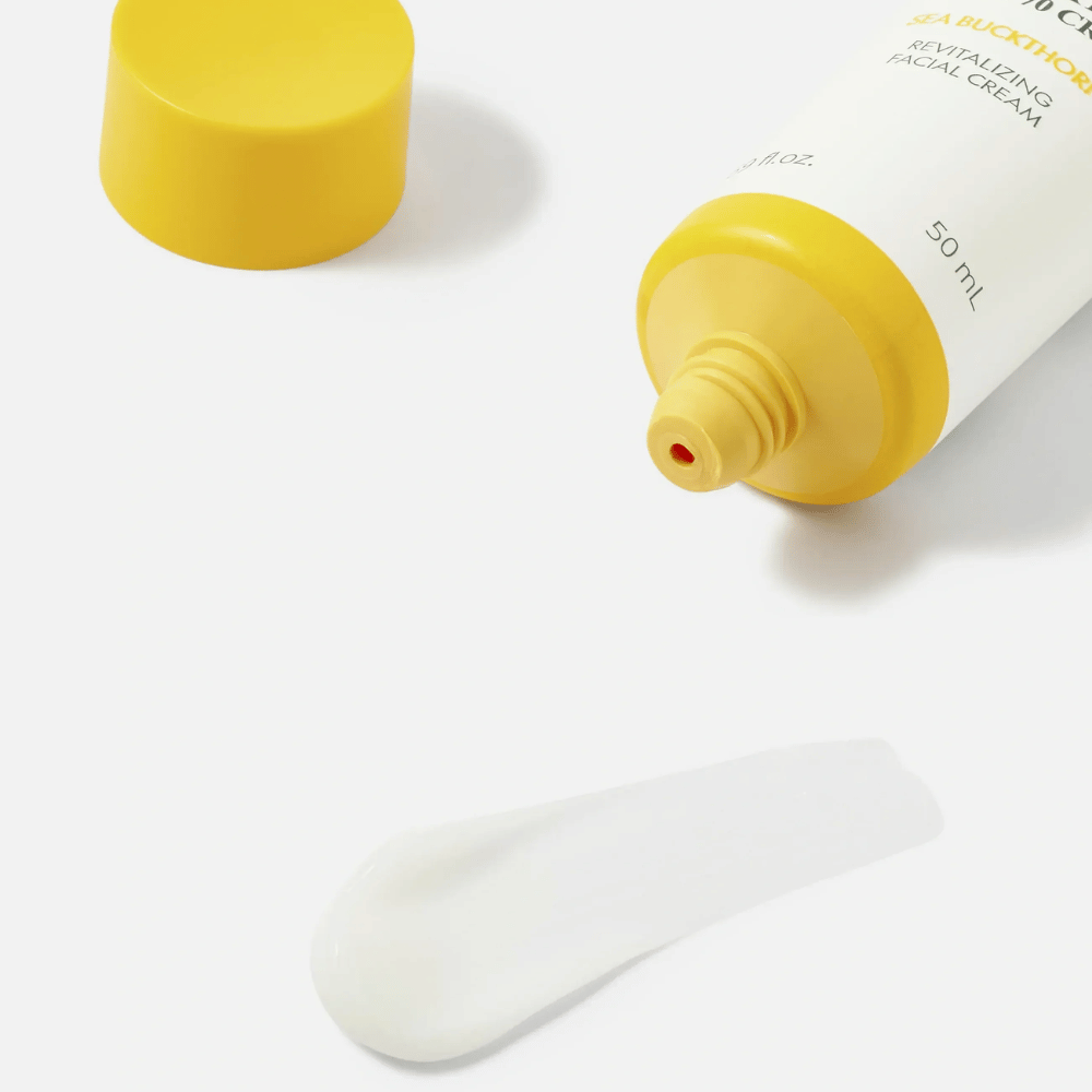 1. Purito SEOUL Sea Buckthorn Vital 70 Cream – zbliżenie lekkiej białej konsystencji kremu do twarzy obok otwartej tubki z żółtą zakrętką